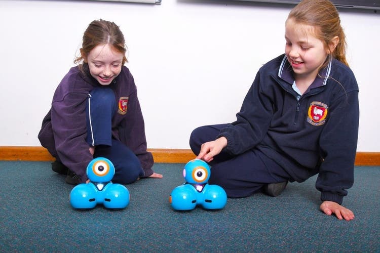 Two students sitting on the floor using robots