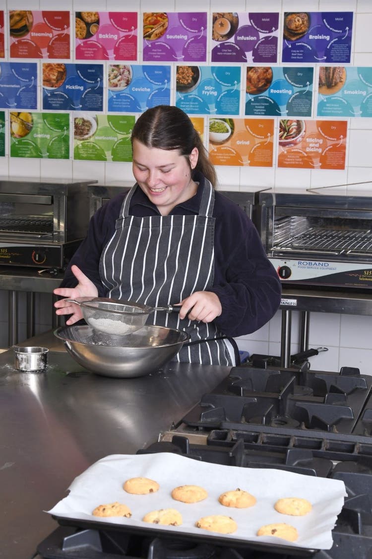 A student sifting flour in the school kitchen