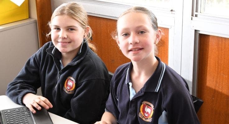 Two students at a desk working on a laptop