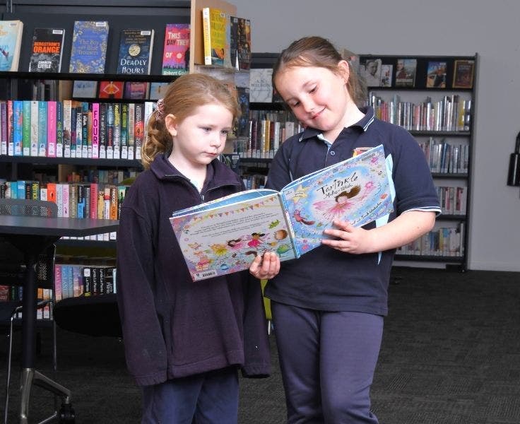 Two students looking at a picture book in the library